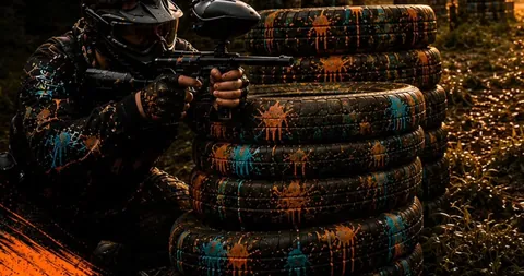 Jugador de paintball cubierto detrás de una barricada de neumáticos