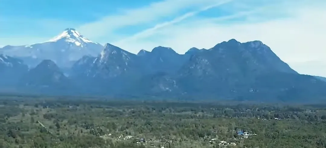 Volcán nevado y cordillera sobre el valle, vistos desde un dron
